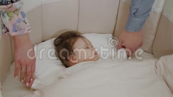 两个父母站在孩子的床边把他抱在怀里视频的预览图