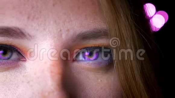 金色女性的特写半肖像紫色的眼睛明亮和五颜六色的化妆在粉红色的灯光背景视频的预览图