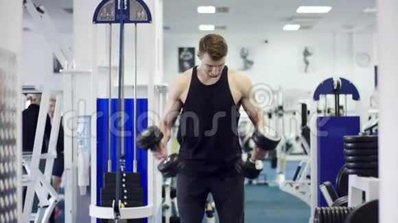 年轻健美运动员在健身房用哑铃锻炼视频的预览图
