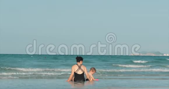 快乐和无忧无虑的母子在海边玩耍晒日光浴游泳儿童和成人在热带海域玩耍视频的预览图