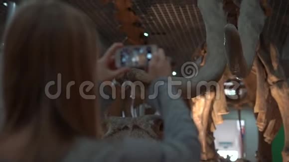 一名年轻女子在手机上拍摄一具猛犸骨骼的照片视频的预览图