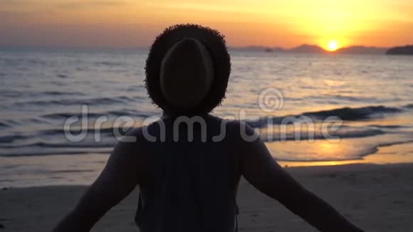 年轻的男性旅行背包客背后的剪影做和平行动v在日落和热带夏季海滩上签名手指视频的预览图
