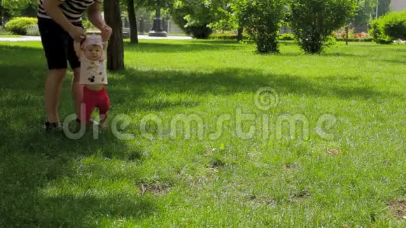 爸爸帮助女儿在草地上的公园里迈出第一步视频的预览图