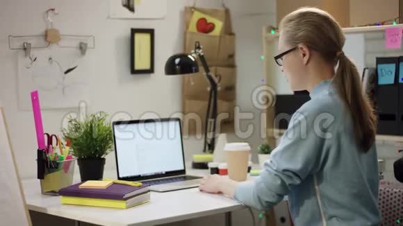 年轻女孩在笔记本电脑上做作业桌子上放着咖啡视频的预览图