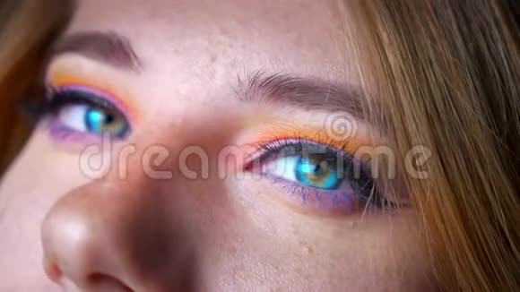 蓝眼睛的金发女性的特写镜头在蓝灯背景上用五颜六色的化妆拍摄视频的预览图