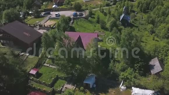 飞过小镇美丽的房子有明亮的粉红色屋顶树在翅膀和绿色的草坪中摇曳剪辑视频的预览图