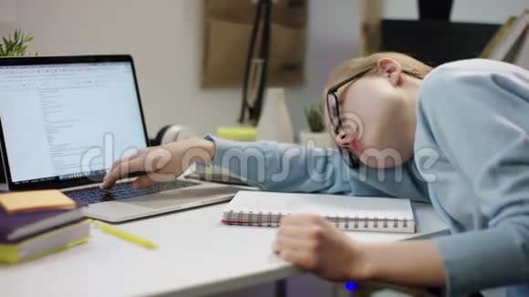 年轻懒惰的女学生躺在桌子上用笔记本电脑视频的预览图