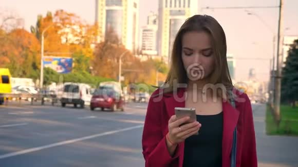 年轻有魅力的女性站在路边的人行道上烦恼地打着视频的预览图