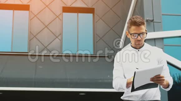 一个年轻的商人站在办公室手里拿着一个文件夹DD视频的预览图