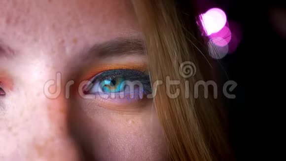 金色女性的特写半肖像有着蔚蓝的眼睛明亮而五颜六色的化妆在粉红色的灯光背景下视频的预览图