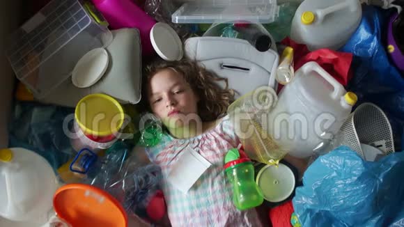 小女孩闭上眼睛看着周围的塑料垃圾塑料袋和垃圾环境污染概念视频的预览图