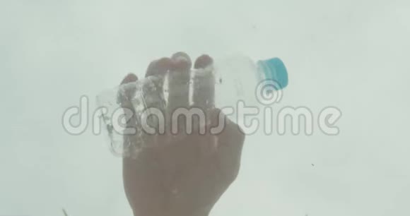 男性手向海水中扔塑料瓶的特写镜头污染问题视频的预览图