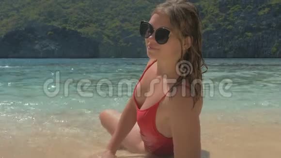 年轻女孩穿着红色泳衣在阳光明媚的日子在热带海滩放松概念自由生活方式旅游度假视频的预览图
