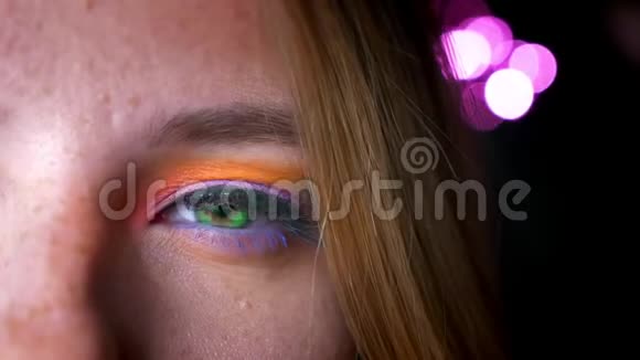 金色女性的特写半肖像绿色的眼睛明亮和五颜六色的化妆在粉红色的灯光背景视频的预览图