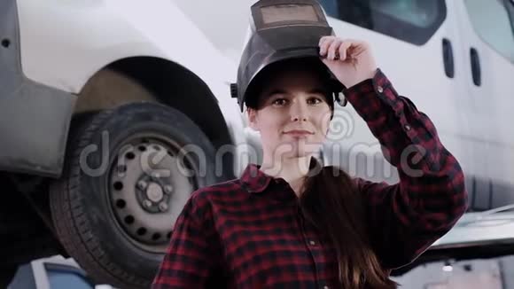 女孩电焊工一个漂亮的黑发女孩戴着电焊工防护头盔的肖像视频的预览图