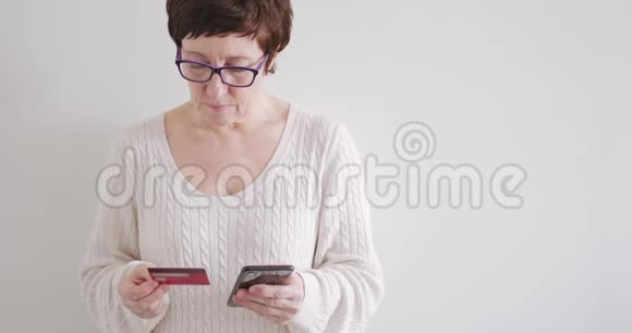 戴眼镜的布鲁内特女士用电话和信用卡在网上商店购物视频的预览图