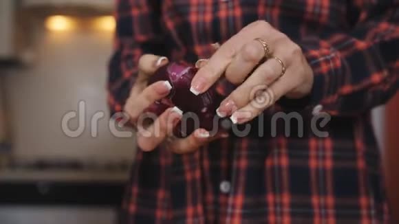 女人用手和刀剥一个红色的洋葱视频的预览图