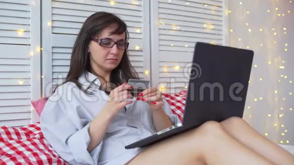 持有信用卡并使用笔记本电脑的女人视频的预览图