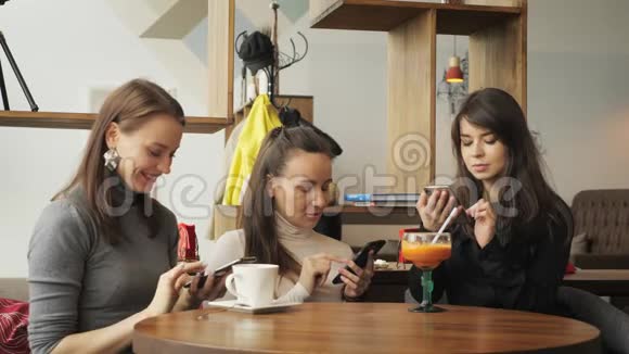 咖啡馆里的三个女朋友正在浏览他们的手机咖啡馆里的友好会议视频的预览图