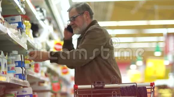 退休人员在超市购物打电话男人在奶酪部门买东西视频的预览图