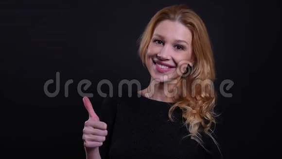 成年红发女性的特写镜头她竖起大拇指微笑着看背景镜头视频的预览图