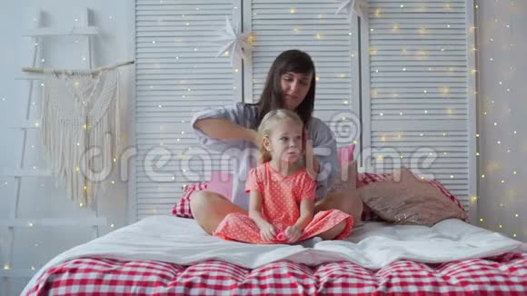 妈妈把女儿的头发刷在床上视频的预览图
