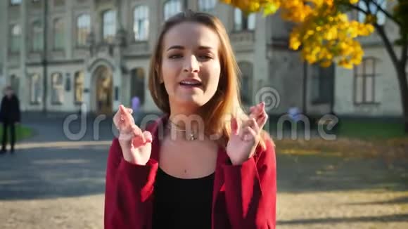 年轻的女学生既担心又紧张她的手指在考试前交叉在大学外视频的预览图