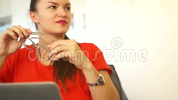 办公室里年轻明亮的黑发那个女孩穿着一件红色的衣服上班休息看远点笑衣服视频的预览图