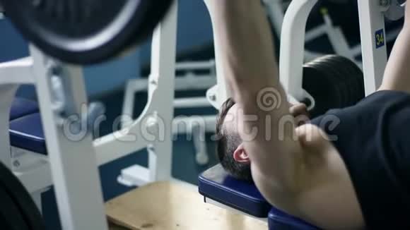 健身者在健身房里用杠铃躺在长凳上锻炼身体视频的预览图