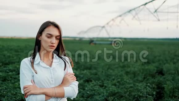 一幅美丽的年轻女孩站在田野里在夕阳下看着相机的肖像现代农业快乐青年视频的预览图