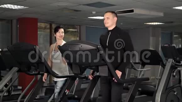 一个年轻女孩和一个男人在跑步机上健身房锻炼体育运动保健视频的预览图