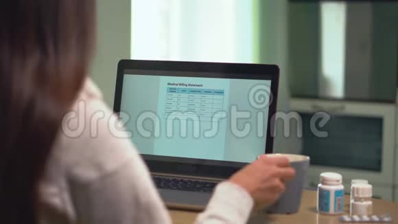 女人看着笔记本电脑屏幕上的医疗账单视频的预览图