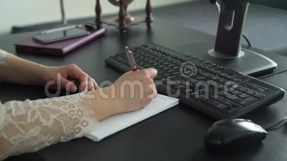 女性在笔记本上做笔记在电脑上打字视频的预览图