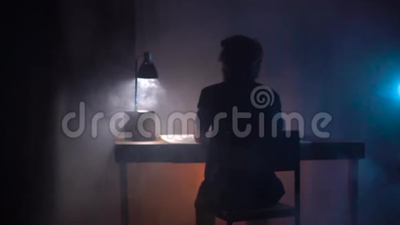 男人艺术家坐在桌子旁用纸和图案素描在黑暗的艺术工作室里烟雾缭绕看着一边视频的预览图