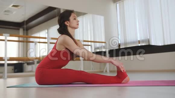 在大厅里坐在垫子上做瑜伽的女人女人做瑜伽练习视频的预览图