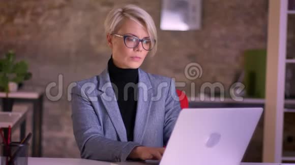 金发短发的女商人戴着眼镜在办公室工作喉咙痛几乎不咳嗽视频的预览图