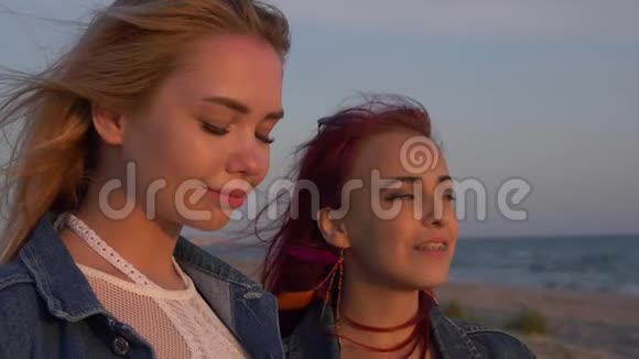 两个年轻的女人在夕阳的温柔光线下在大海的背景下冲浪视频的预览图