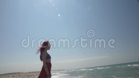 戴墨镜的红发年轻女子站在一片海浪中视频的预览图