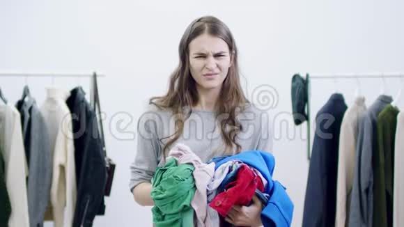愤怒的漂亮女孩把衣服扔到更衣室里的摄像机视频的预览图