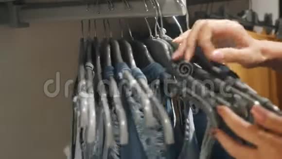 女人的手透过挂在服装店衣架上的衣服视频的预览图