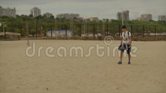 男人带着自拍棒在荒芜的海滩上散步视频的预览图