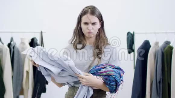 严肃的年轻女人把衣服扔进了一间服装室的摄像机视频的预览图