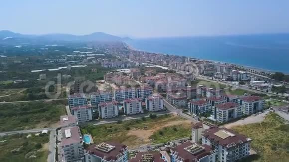 从空中俯瞰希腊沿海城市艺术许多建筑和房屋建在蓝色前面的丘陵地区视频的预览图