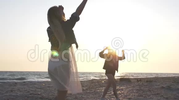 傍晚时分穿着牛仔夹克的年轻女性在夕阳的余晖中在海滨玩得很开心视频的预览图