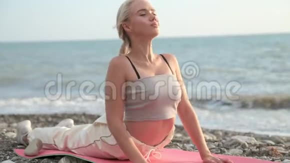在夏季户外海边的沙滩上运动的年轻女子在瑜伽垫上伸展背部视频的预览图