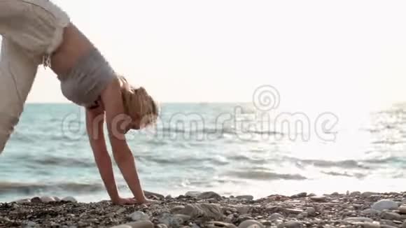 一位身材矮小运动力强的海边女子仰着腰背起身来双手放在地板上锻炼身体以保持身体健康视频的预览图
