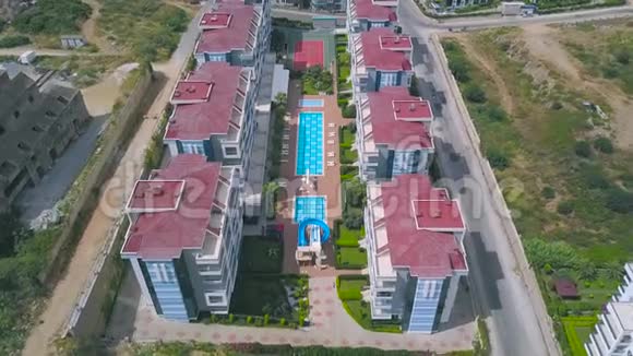 酒店自上而下的鸟瞰游泳池蓝色的水周围有其他建筑物和绿色草坪艺术视频的预览图