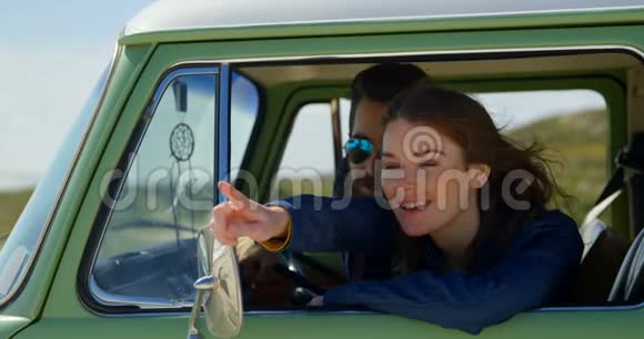 微笑着美丽的女人用手指指着车上的男人视频的预览图