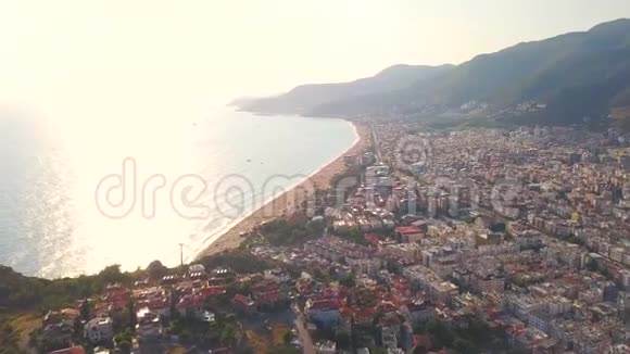 鸟瞰向城市飞去一座山迎着海面上的夕阳艺术阳光下的迷人海景视频的预览图