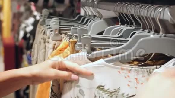 女性的手在衣架上奔跑在服装店寻找衣服视频的预览图